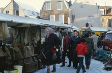 851894 Afbeelding van een enkele kramen met tweedehands spullen op de rommelmarkt op een besneeuwd braakliggend terrein ...